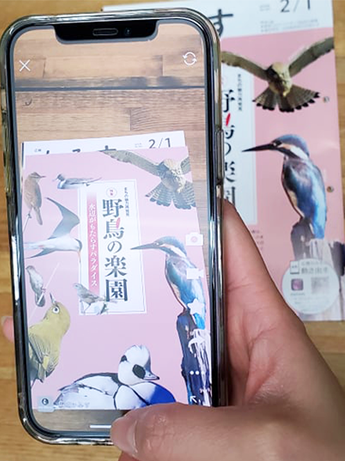 広報紙にスマートフォンをかざす様子